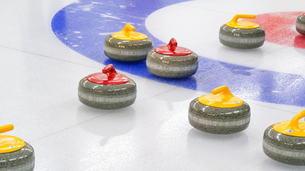 Curling winter, olympic sport.Curling stones on ice curling sheet with red and blue circle and visible pebbles 