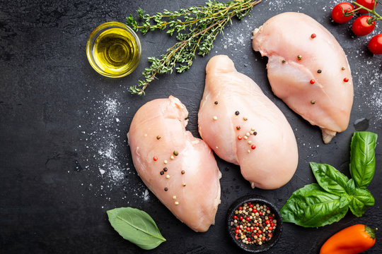 Fresh raw chicken breast with herbs and spices, top view. Culinary cooking ingredients