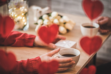 Valentines day.  Close-up of female and man celebrating in restaurant with gifts and flowers. View through a heart-shaped garland. love, romance, date