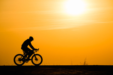 Obraz na płótnie Canvas Silhouette man cycling on sunset background