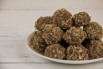 Energy balls homemade healthy candy without sugar in a white plate on a white-wooden background
