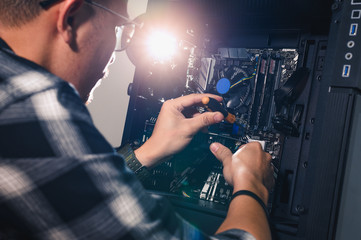 The technician hold the screwdriver for repairing the computer. the concept of computer hardware,...