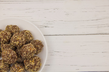 Energy balls homemade healthy candy without sugar in a white plate on a white-wooden background