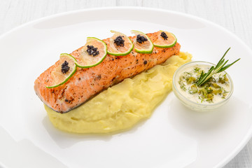 Grilled salmon, boiled potatoes and vegetables on a white plate