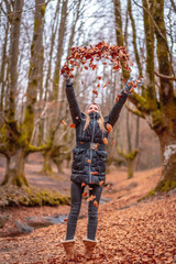 Blonde girl throwing leaves in a beautiful forest in winter