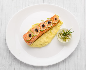 Grilled salmon, boiled potatoes and vegetables on a white plate