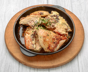 Baked spicy chicken legs in garlic sauce in a cast iron pan