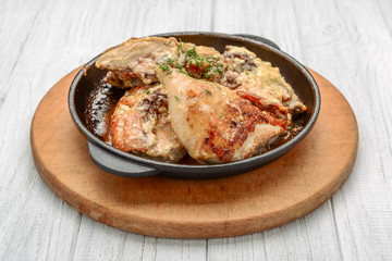 Baked spicy chicken legs in garlic sauce in a cast iron pan