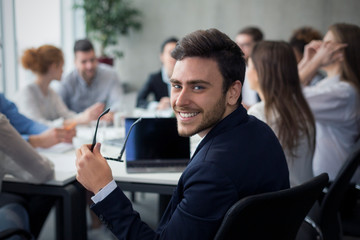 Happy corporate businessman smiling to camera at meeting