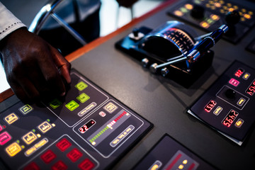 Boat captain hands navigating and moving instruments in the cockpit.