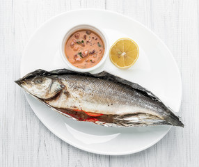 Baked sea bass with vegetables close up shoot on wooden background