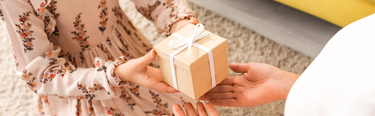 partial view of elegant child presenting mothers day gift to mom while sitting on floor, panoramic...