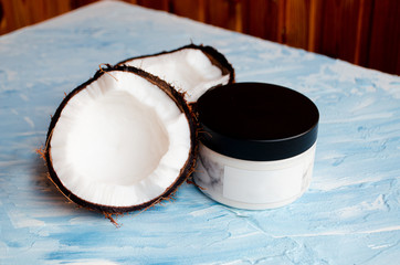  Coconut skin cream and two halves of coconut on a blue texture background