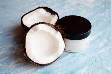  Coconut skin cream and two halves of coconut on a blue texture background