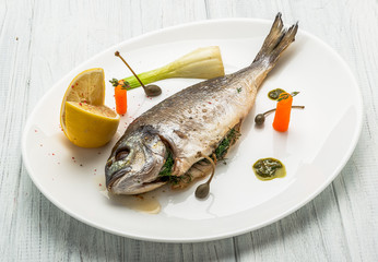 Grilled fish on platter isolated on white. Top view of whole roasted dorado