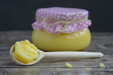ghee oil in a jar with a wooden spoon on a wooden table