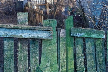 old wooden fence made of gray green boards on the street