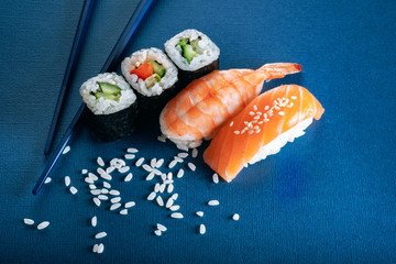 Sushi set with salmon and shrimp, and cucumber rolls on a blue background