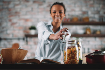 Young mixed race woman in kitchen. Beautiful woman cooking pasta. 