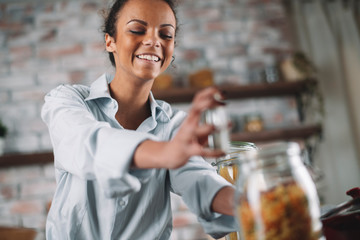 Young mixed race woman in kitchen. Beautiful woman cooking pasta. 