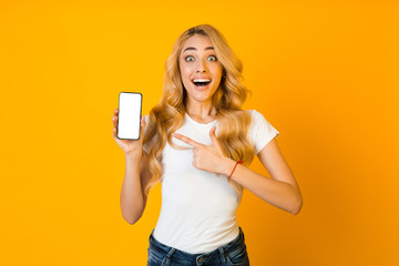 Naklejka premium Wow sales. Surprised woman pointing at blank phone screen