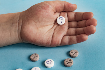 Tablets with smiley face. The concept of antidepressants and healing. Child taking pill, holding white tablet in hand. Concept of medication, antidepressant or vitamin