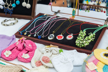 Closeup of handmade accessories and knitted baby shoes showcased on stalls. Original items sold by local craftsmen and designers on a crafts and arts outdoor market in Chisinau, Moldova