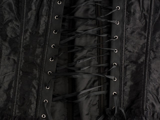 fragment of a black satin corset with lacing, back view