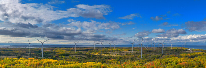 The Windmills park of Paldiski panorama. Wind turbine farm near Baltic sea. Autumn landscape with windmills, orange forest and blue sky. Pakri peninsula, Estonia, Europe.