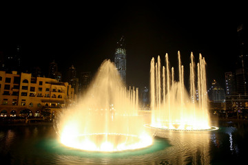 Water & Light show in the downtown city at night with all the skyscrappers illluminated and reflecting in the lake, Dubai, United Arab Emirates.