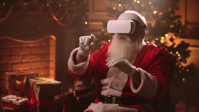 Santa claus is putting on vr helmet and surfing virtual reality, isolated on christmas spirit, technology concept close up 4k footage.