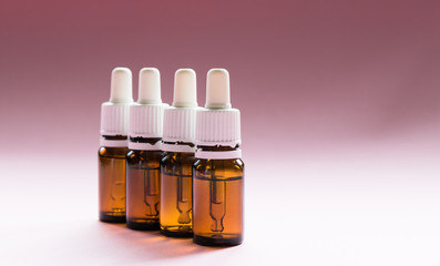 cosmetology, glass bottles with pipettes and cosmetic on a pink background