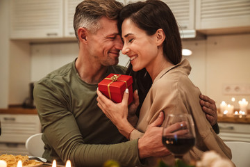 Image of man giving present box to his girlfriend during romantic dinner