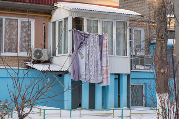 lingerie dries in winter on a rope on the street, a blue house, bushes