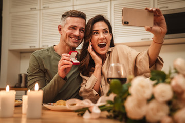 Image of couple taking selfie with engagement ring while having dinner
