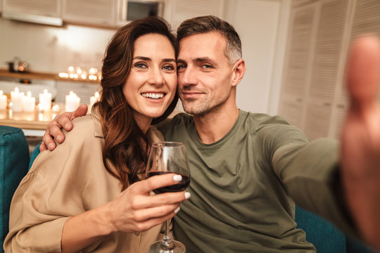 Image of couple taking selfie while having candlelight dinner at home