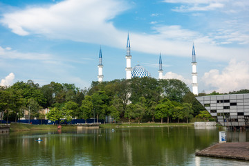 Sultan Salahuddin Abdul Aziz Shah Mosque in Shah Alam, Malaysia during blue skies sunny day with Shah Alam lake in foreground. It is also known as Blue Mosque.