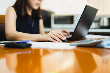 Businesswoman hand holding computer mouse working on wooden desk.