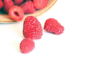 Raspberries on a white background. Harvesting fresh raspberries in June. Sweet red berry. Raspberry Farm. Basket with ripe berries.