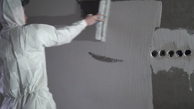 Construction worker plastering and smoothing concrete wall with putty. Putty and leveling walls for subsequent painting. Worker making repair in room. Builder using plastering tool for finishing wall