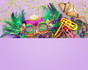 Purim celebration concept (jewish carnival holiday) over purple wooden background. Top view, Flat lay