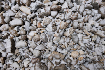 Snow covered round rock and stones. Colorful rock landscaping with snow.