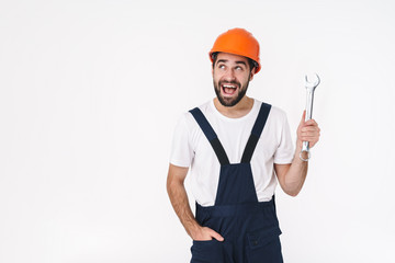 Positive young man builder holding wrench.