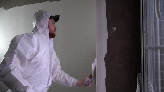 Construction worker plastering and smoothing concrete wall with putty. Putty and leveling walls for subsequent painting. Worker making repair in room. Builder using plastering tool for finishing wall