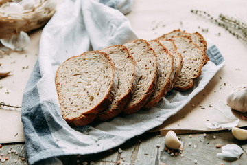  Garlic and thyme with pastries. A loaf of white rye bread. Sliced bread on a wooden Board. Slices on a towel.