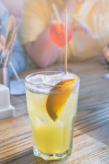 Glass of soda with orange slice and eco friendly tube on wooden table in cafe. People drinking squash using eco bamboo straw. Plastic free concept.