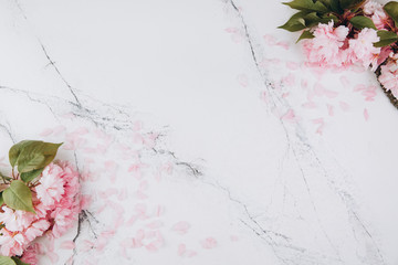 Sprigs of the sakura tree with flowers and petals on trendy marble background. Place for text. The concept of spring came. Top view. Flat lay