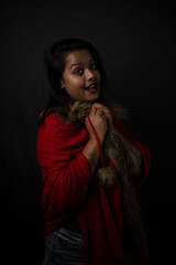 Fashion portrait of an young Indian Bengali brunette woman with black lingerie and furry shrug in black copy space background. Indian lifestyle and fashion photography.