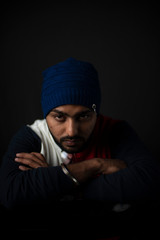 Fashion portrait of an young Indian Bengali brunette man in casual tee shirt and head band in black copy space background. Indian lifestyle and fashion photography.