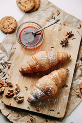 Flatley layout with nuts and powdered sugar. Croissants with raspberry jam. Fresh pastries on a wooden background.